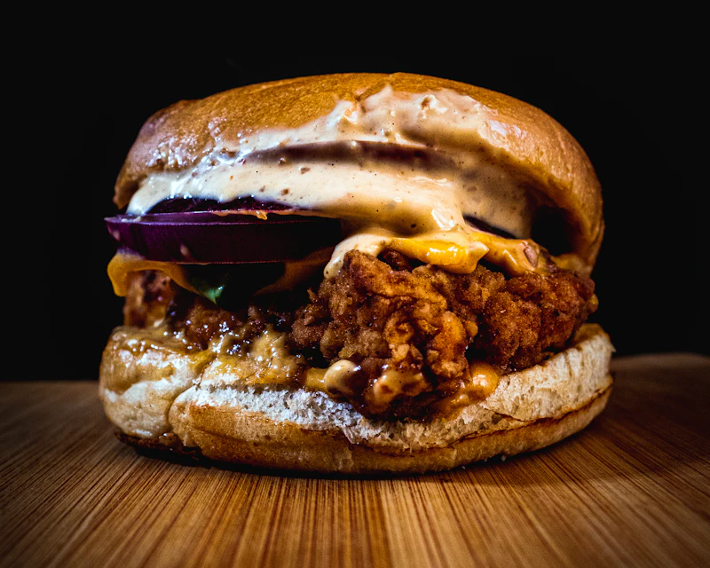 Crispy chicken burger with creamy butter sauce and red onion