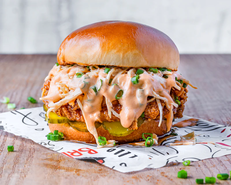 Crispy chicken burger piled with glazed sauce and spring onions