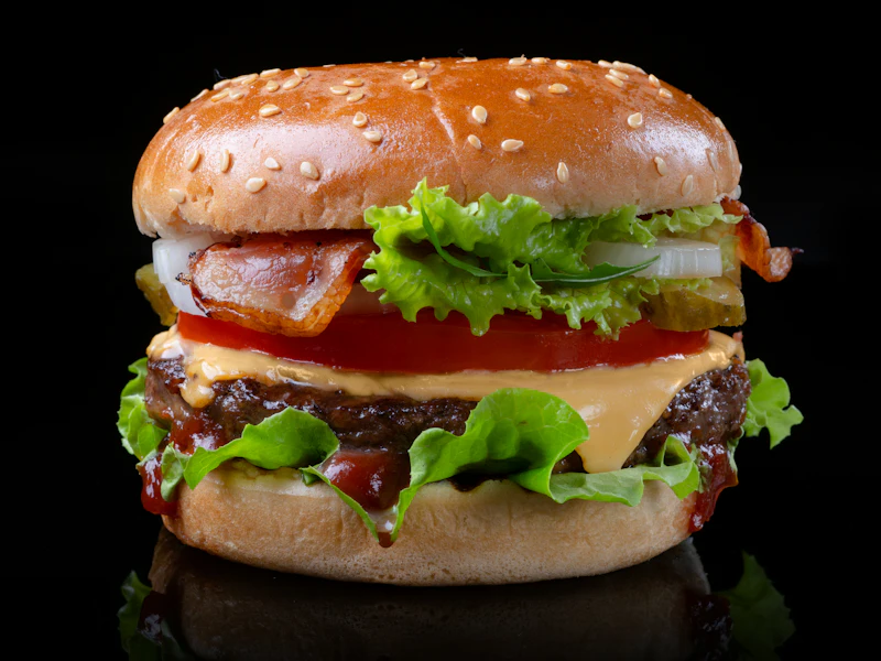 Big Meat Beast: a tall, juicy beef burger with lettuce, tomato and melted cheese on a black background