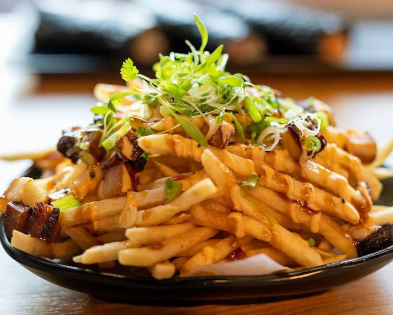 Fries topped with chicken, orange butter sauce and fresh herbs