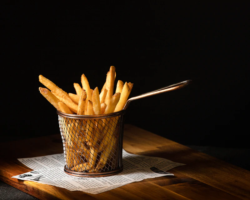 Golden french fries in a wire basket on a dark table