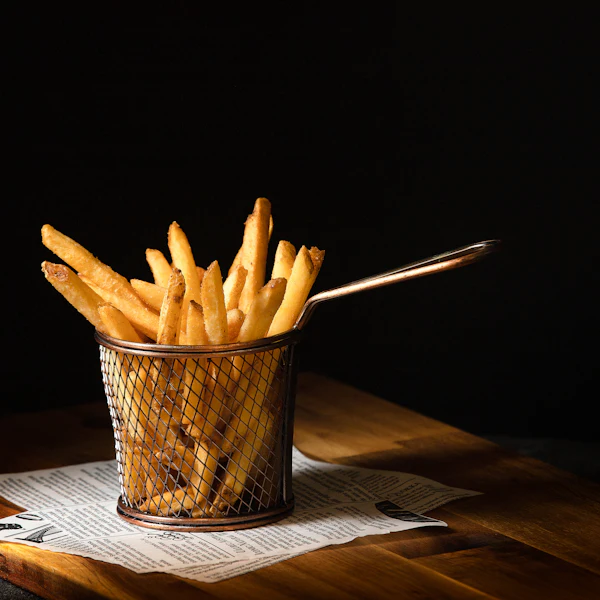 Golden fries in a wire basket on a dark table