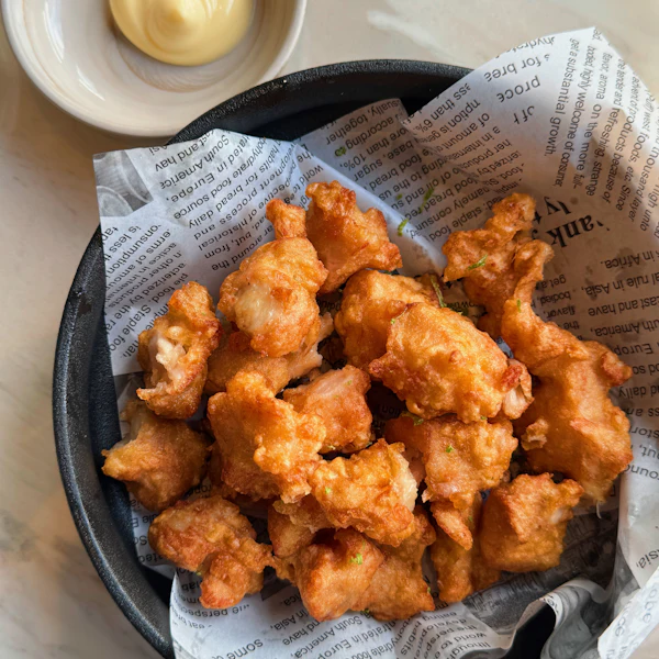 Basket of crispy popcorn chicken with a creamy dip
