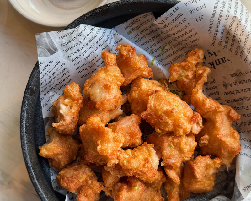 Basket of golden popcorn chicken with a creamy dip