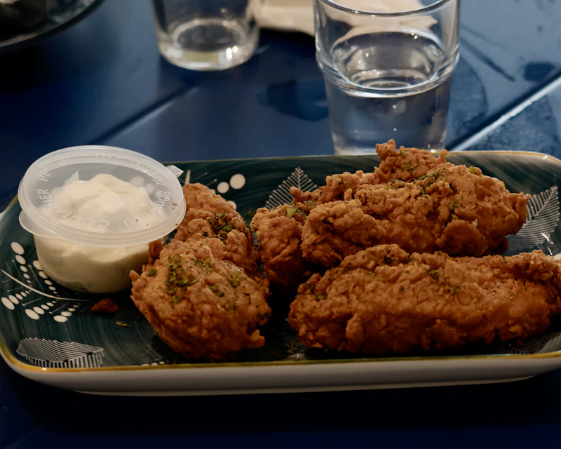 Crispy chicken tenders on a tray with a creamy dip